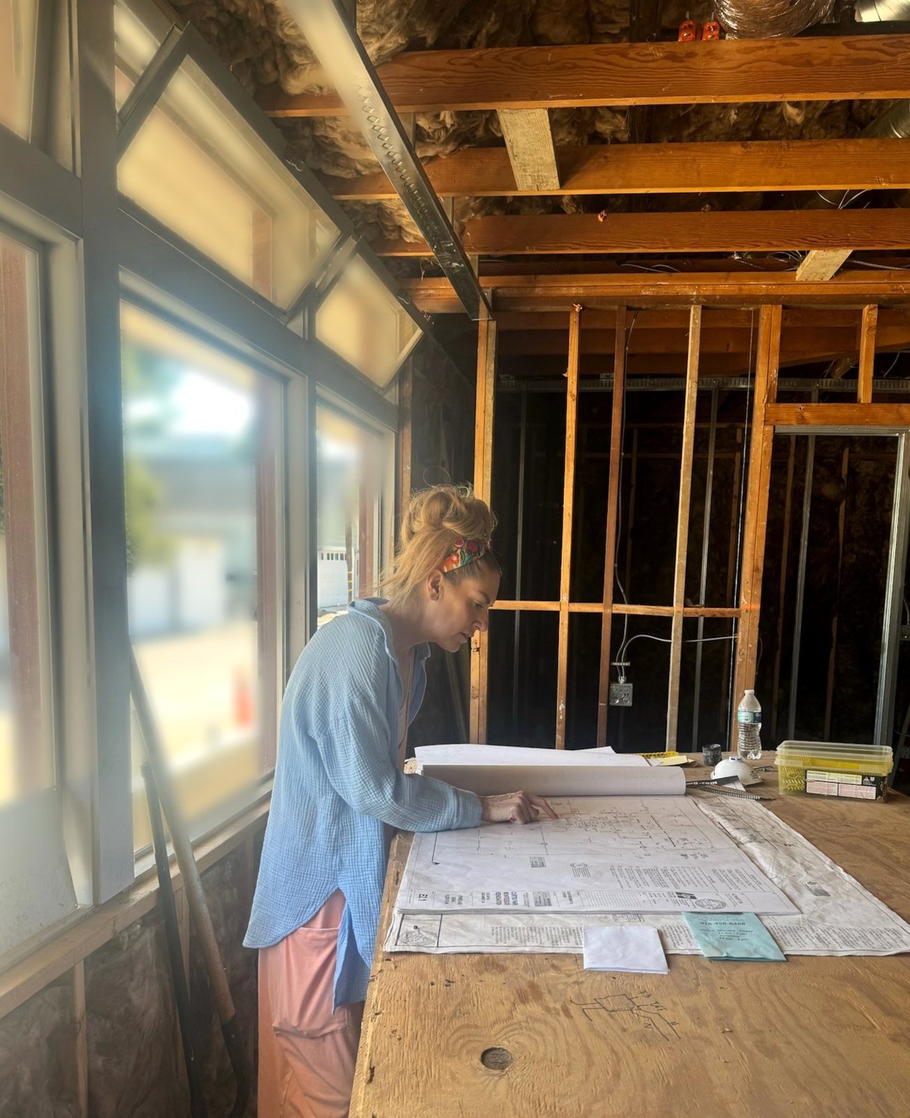 Aimee Gandy reviewing building plans at a work table inside the school during construction